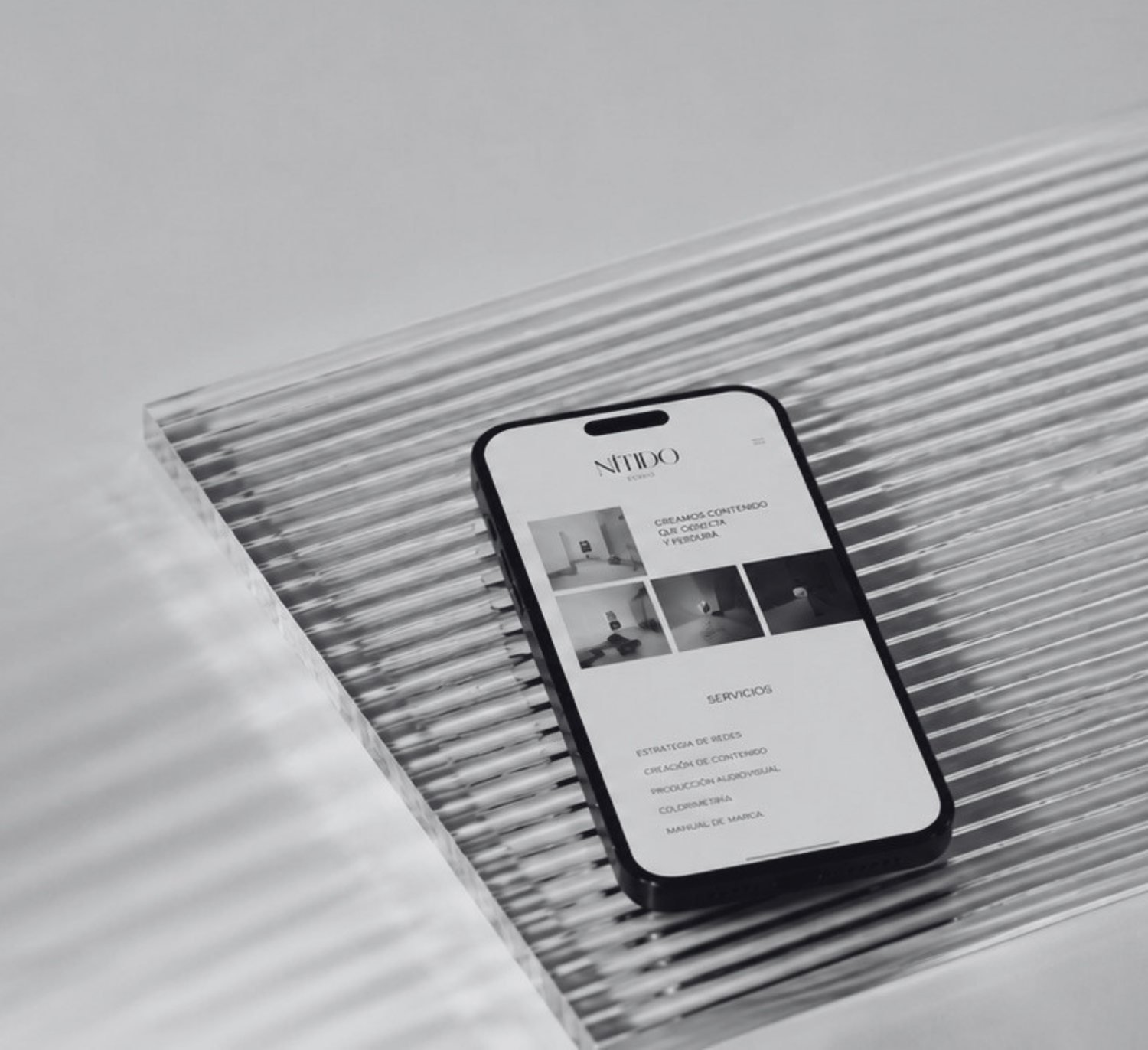 Teléfono sobre vidrio estriado mostrando contenido y servicios de redes de Nítido
