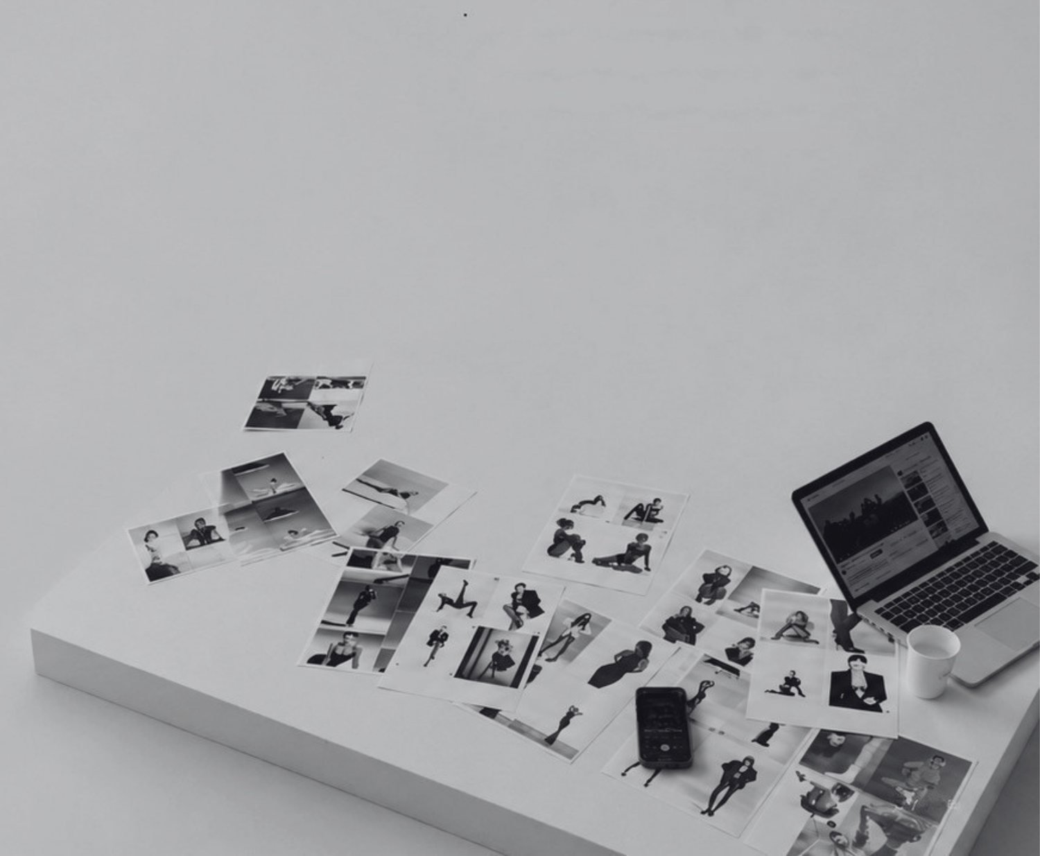 Mesa de edición con copias fotográficas ordenadas junto a un portátil